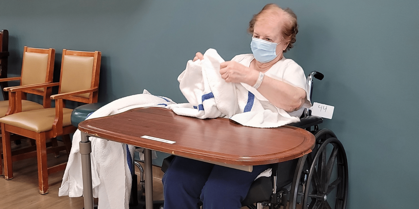Short term rehab patient folding laundry during occupational therapy session