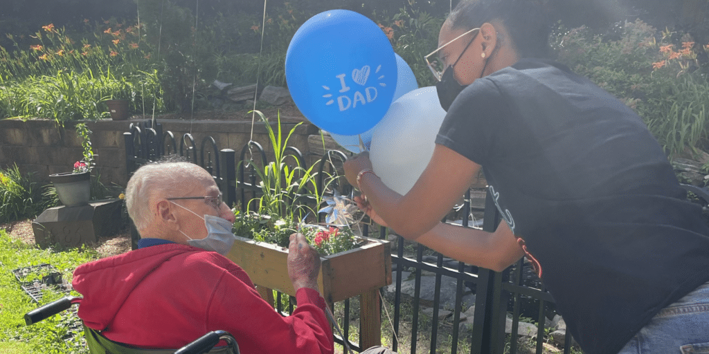 Senior man receiving Father's Day balloons in outdoor setting