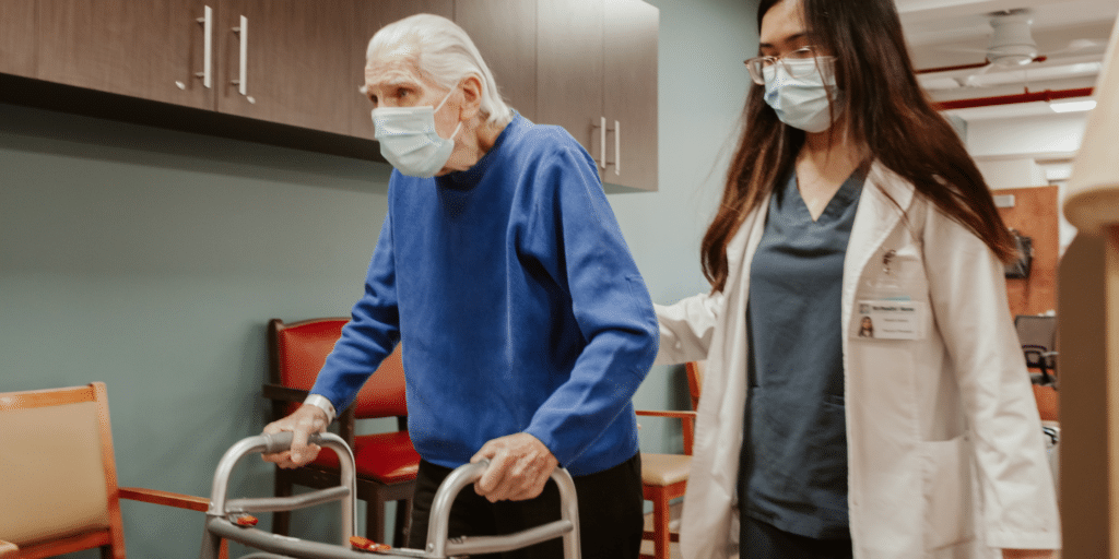 Senior man walking next to physical therapist during session