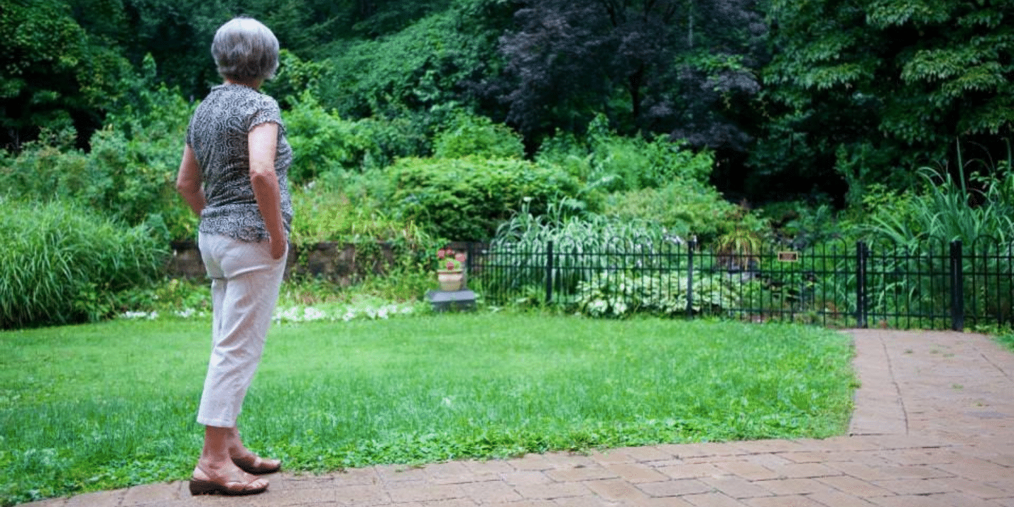 Woman standing alone looking at the Methodist Home gardens in Bronx, NY