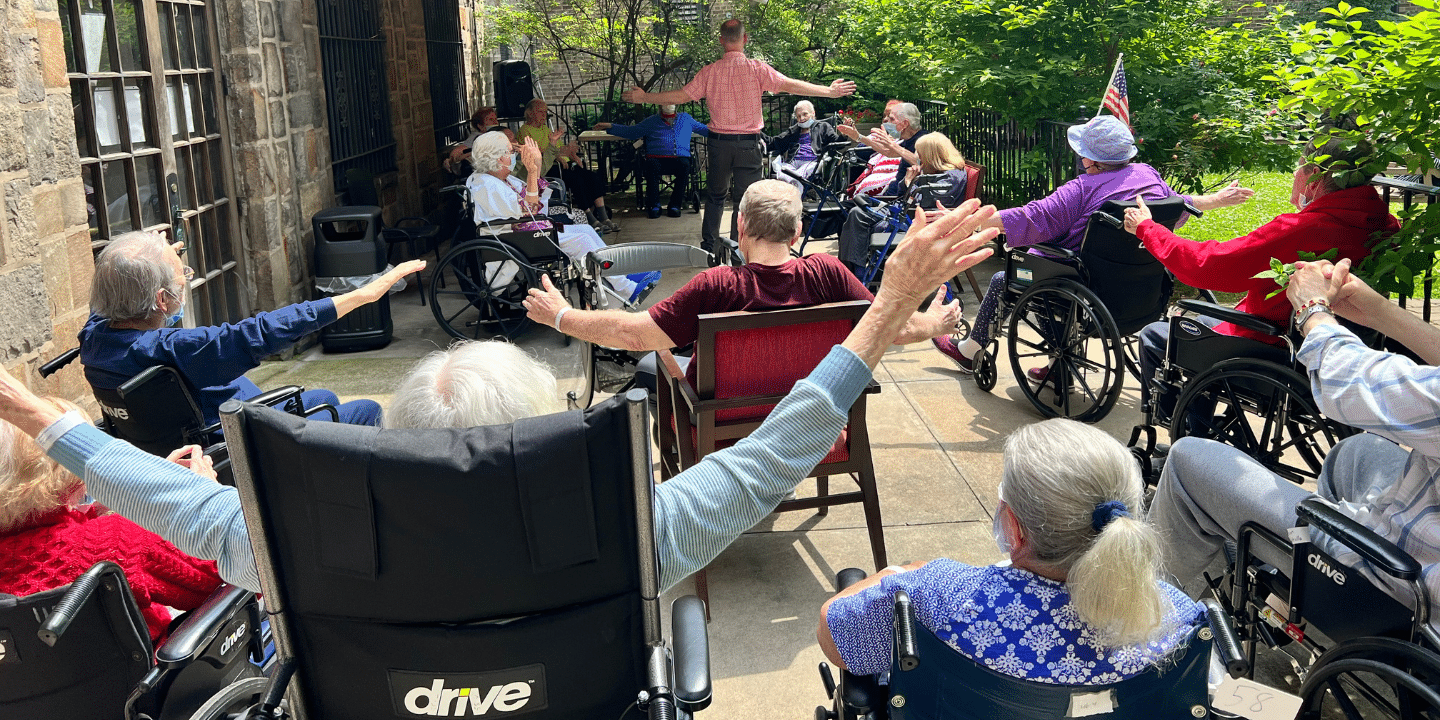 Photo of seniors on outdoor patio enjoying a chair stretch exercise