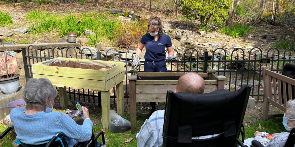 Featured blog post image showing Methodist Home staff Anny during a gardening session with a few Garden Club members