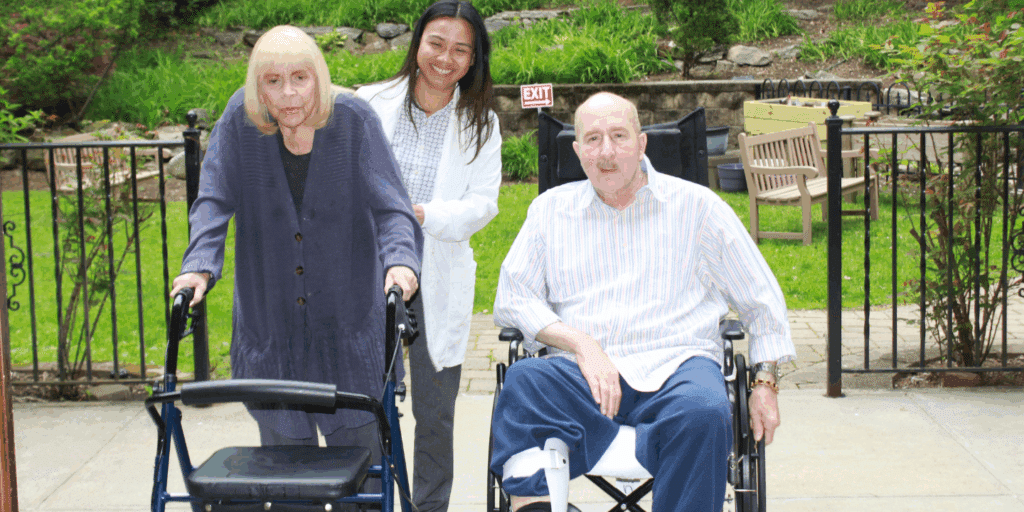 Photo of two short term rehab patients with a therapist enjoying some outdoor physical therapy in the gardens to prevent falls and injuries. Photo taken in the the Methodist Home on a bright, sunny day in the Bronx, NY.